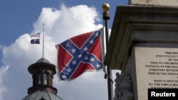 FILE - The U.S. flag and South Carolina state flag flies at half staff to honor the nine people killed in the Charleston murders as the confederate battle flag also flies on the grounds of the South Carolina State House in Columbia, S.C., June 20, 2015. 