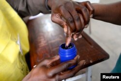 A voter's finger is marked after voting in the general election in Maputo, Oct. 15, 2014.