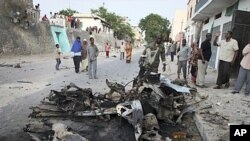 Somalis observe the remains of a vehicle used in a car bomb attack in the capital Mogadishu, Somalia, February 8, 2012.