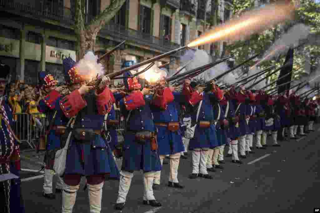 Men wearing reproductions of Catalan military costumes of the 18th century shoot blaze weapons during a performance during the Catalan National Day in Barcelona, Spain.