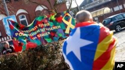 Un hombre llevando una bandera catalana camina cerca de la prisión de Neumünster donde permanece el expresidente Carles Puigdemont. La pancarta dice "Libertad a los prisioneros políticos en España".