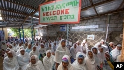 Members of Ethiopia's Jewish community gather below a banner reading "Welcome" in Amharic, English and Hebrew, to protest the Israeli decision not to allow all of them to emigrate to Israel, leaving their families divided between the two countries, in Addis Ababa, Nov. 19, 2018. 