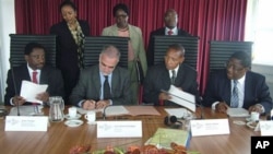 In this photo taken by International Criminal Court, first row from left: Kenya's Justice Minister Mutula Kilonzo, ICC's prosecutor Luis Moreno-Ocampo, Kenya's Minister of Lands James Orengo, as they sign an agreement at ICC in The Hague, Netherlands, Jul