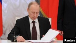Ruski predsednik Vladimir Putin potpisuje sporazum o ratifikaciji sporazuma kojim Krim postaje deo Rusije na ceremoniji u Kremlju 21. marta 2014. 