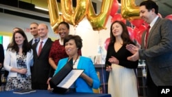 District of Columbia Mayor Muriel Bowser, seated, holds the LOVE Act she signed, Jan. 11, 2019.