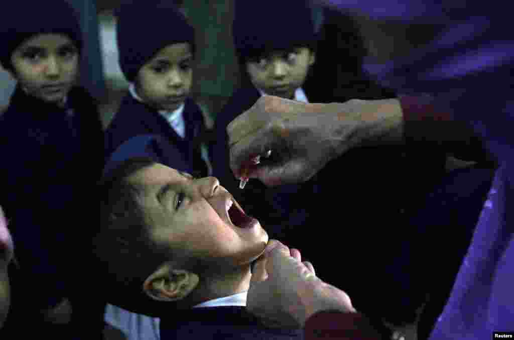 A polio worker gives polio vaccine drops to a child in Lahore, Pakstian, December 20, 2012.