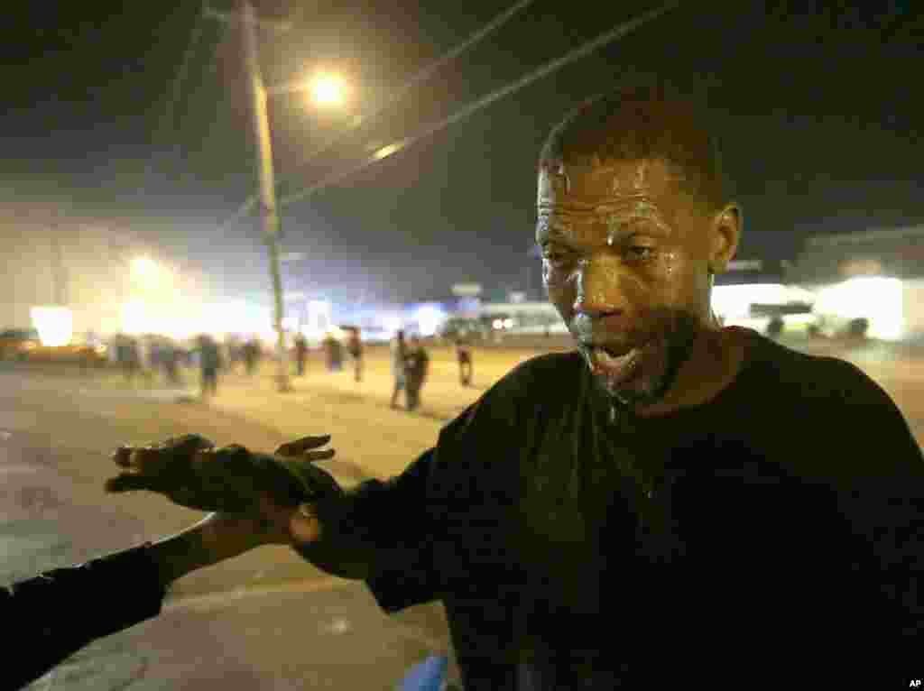 A man tries to recover after being treated for tear gas exposure, Ferguson, Aug. 18, 2014.