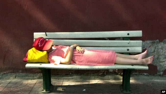 An unidentified girl takes a nap on a bench along the red walls next to Tiananmen Gate in Beijing Sunday, July 15, 2001. (AP Photo/Vincent Yu)