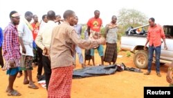 People stand near a body at the scene where a blast killed Kenyan police officers at the Garissa county, eastern Kenya, May 24, 2017. 