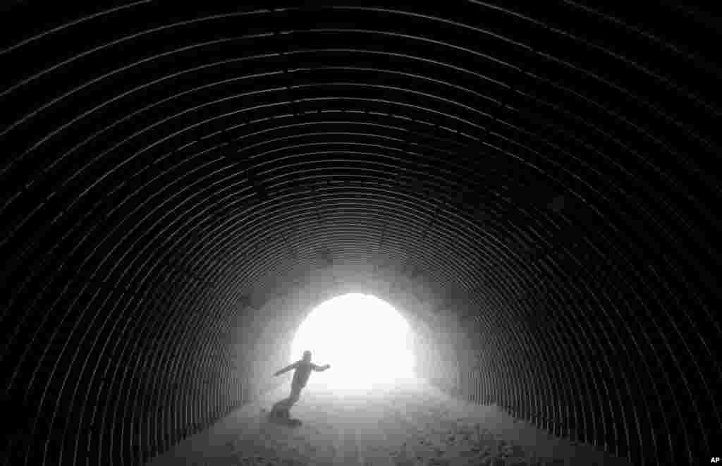 A snowboarder goes through a tunnel near the alpine skiing training slopes at the Sochi 2014 Winter Olympics, Feb. 17, 2014.