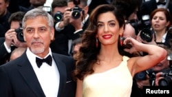 FILE - George Clooney and his wife, Amal, pose on the red carpet during the 69th Cannes Film Festival in Cannes, France, May 12, 2016.