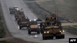 FILE - A convoy of US military vehicles is seen in Syria's northern city of Manbij, Dec. 30, 2018. The US-led military coalition in Syria has begun pulling out troops, a spokesman said on Jan. 11, 2019 without elaborating on locations or timetables. 