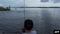 FILE - A boy fishes on a bayou near Isle de Jean Charles, La., Aug. 16, 2015. 