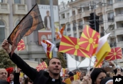 A priest waves a flag to salute Pope Francis as he arrives to celebrate Mass in Macedonia Square, in Skopje, North Macedonia, May 7, 2019.