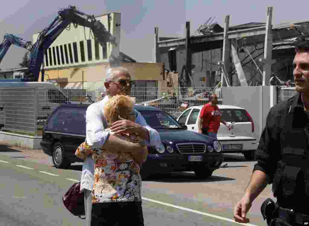 Un poblador de Mirandola de apellido Borghi, quien perdi&oacute; a un hijo en el terremoto, trata de consolar a su esposa frente a la f&aacute;brica de molduras BBG que result&oacute; destruida por el temblor en el norte de Italia este martes 29 de mayo d