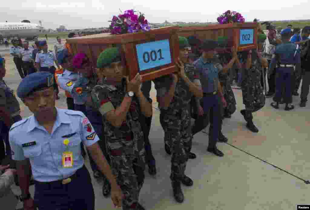 Indonesian military carry the caskets containing the bodies of two AirAsia Flight 8501 passengers recovered off the coast of Borneo, at a military base in Surabaya, Dec. 31, 2014. 