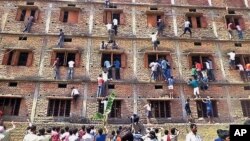 FILE - Indians climb the wall of a building to help students appearing in an examination in Hajipur, in the eastern Indian state of Bihar, March 18, 2014.