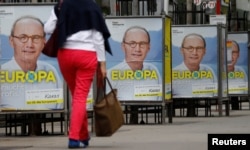 A woman walks past European election posters of the top candidate of Austria's Peoples Party OeVP for the EU elections Othmar Karas in Vienna, Austria, April 26, 2019.