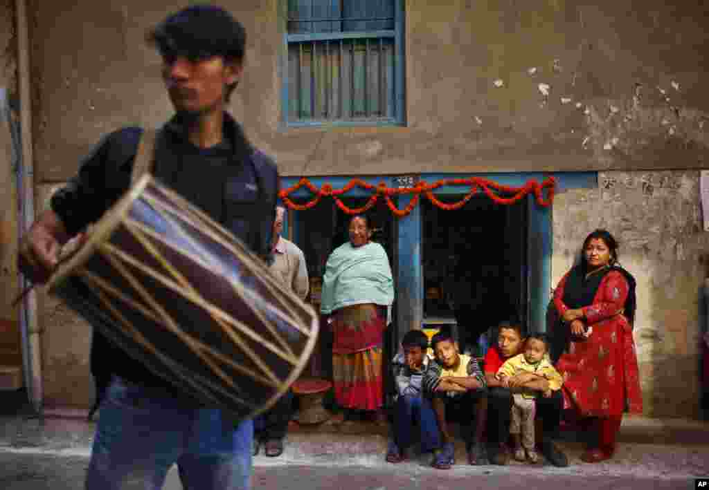 Locals watch as a man beats a traditional drum while participating in a parade to celebrate New Year of the ethnic Newaris in Katmandu, Nepal.