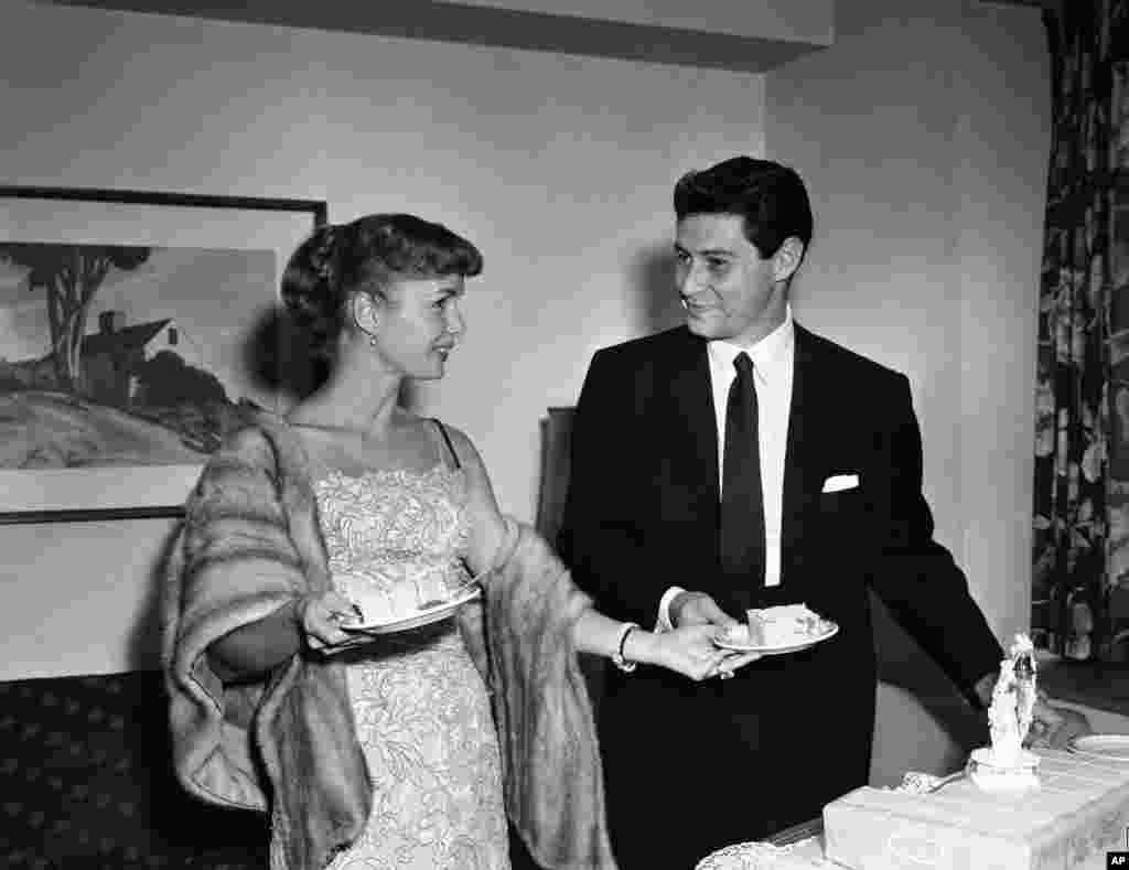 Actress Debbie Reynolds hands her singing husband Eddie Fisher a piece of cake as they pose at a press conference in Washington, D.C., about 24 hours after their marriage at a Catskill mountain resort, Sept. 27, 1955. 