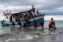 Nelayan lokal membantu warga etnis Rohingya di atas perahu kayu saat mereka tiba di Pantai Lancok, Aceh Utara, 25 Juni 2020. (AP Photo/Zik Maulana)