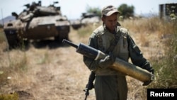 An Israeli soldier carries a tank shell near Alonei Habashan on the Israeli occupied Golan Heights, close to the ceasefire line between Israel and Syria June 22, 2014. 