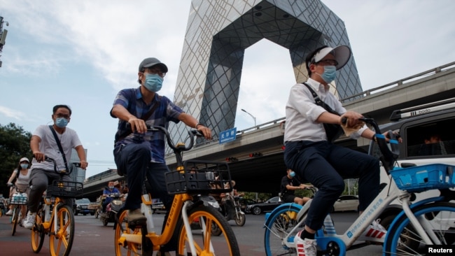 人们骑车路过位于北京中央商业区的中国官媒央视大楼。