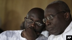 Liberian opposition presidential candidate Winston Tubman, right, talks with running mate George Weah at a rally urging their party's supporters to boycott next week's presidential polls, in Monrovia, Liberia Saturday, Nov. 5, 2011.