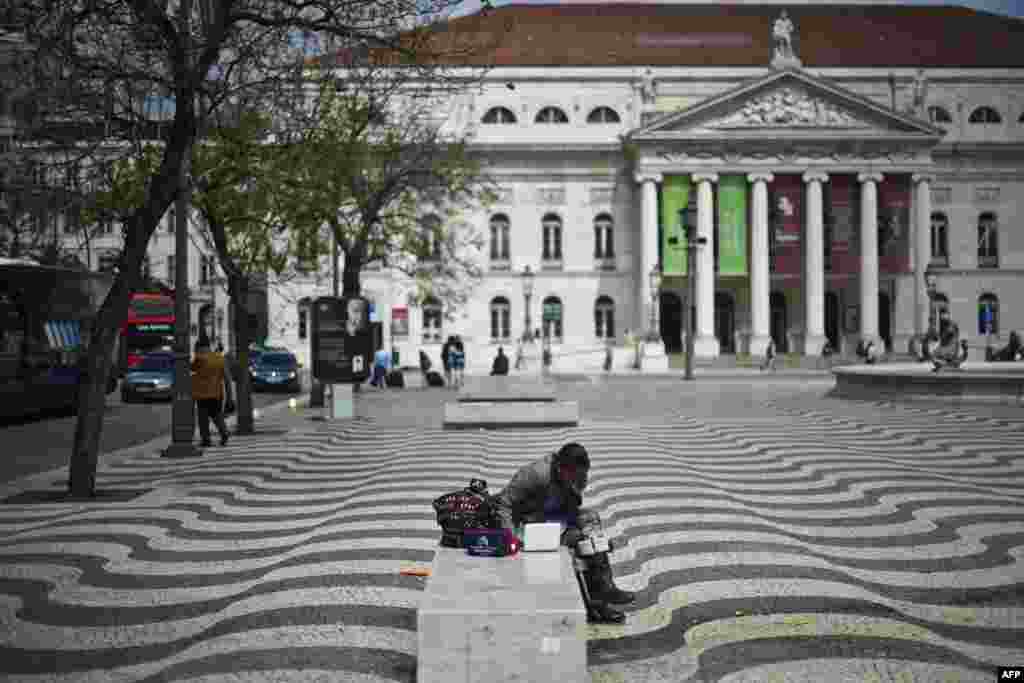 A woman has lunch on a bench at Rossio Square in central Lisbon, Portugal.