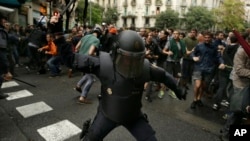 Іспанський поліцейський замахується на прибулих на виборчу дільницю у Барселоні.