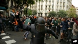 Spanish riot police swings a club against would-be voters near a school assigned to be a polling station by the Catalan government in Barcelona, Oct. 1, 2017.