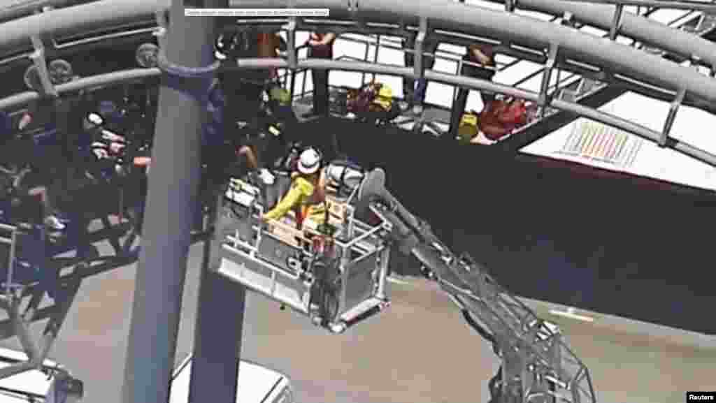 Rescue workers are seen next to people stuck in the Arkham Asylum roller coaster ride at the Warner Bros. Movie World theme park in Gold Coast, Australia, in this still image from video.