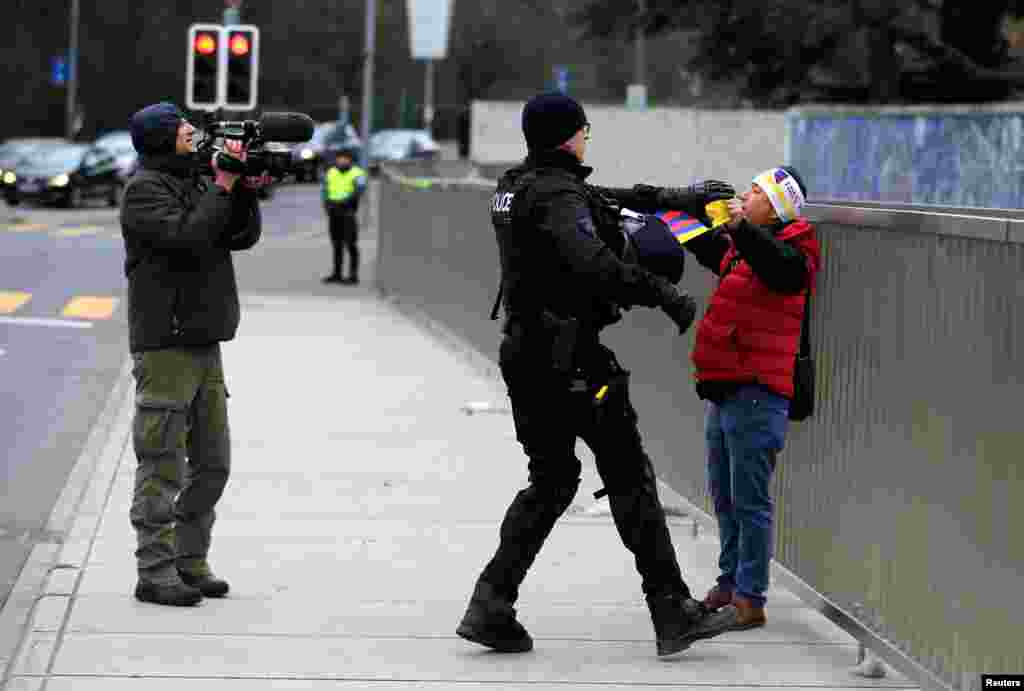 Polisi menahan demonstran yang melakukan protes terhadap Presiden China Xi Jinping di luar kantor PBB di Jenewa, Swiss.