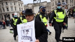لندن میں مظاہرے میں شامل ایک شخص پلےکارڈاٹھائے ہوے