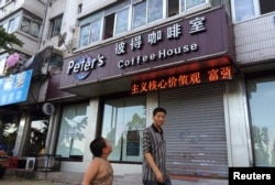 A boy looks up as he walks past the closed coffee shop owned by Canadian couple Kevin and Julia Dawn Garratt in Dandong, Liaoning province, August 5, 2014.