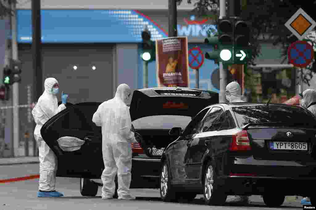 Forensics officers inspect the car of former Greek prime minister and former central bank chief Lucas Papademos following the detonation of an envelope injuring him and his driver, in Athens.