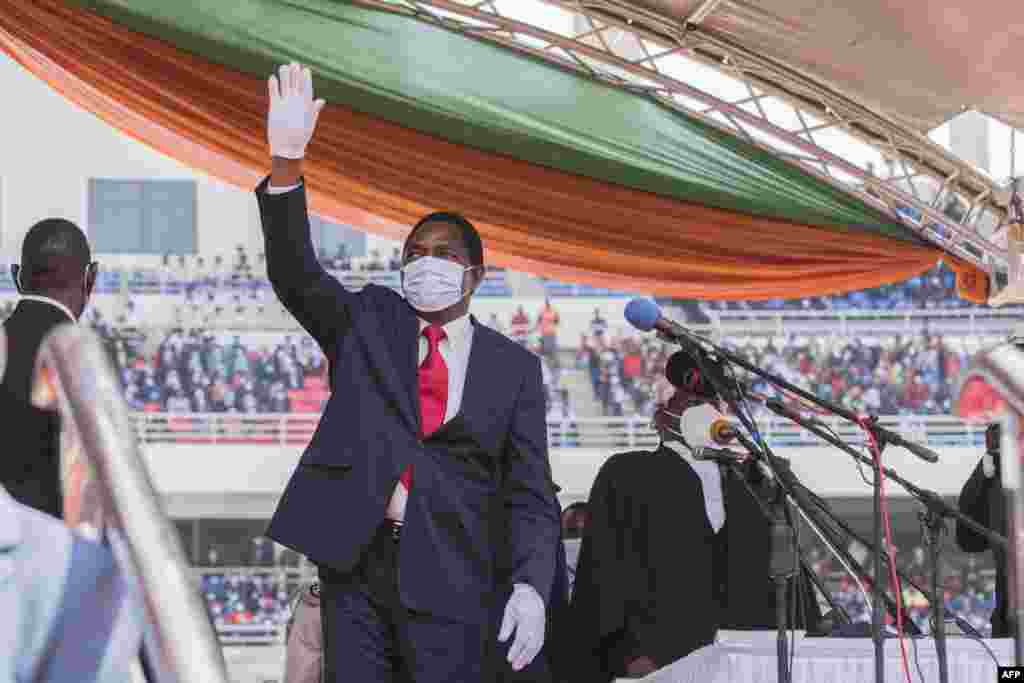 O recém-eleito Presidente da Zâmbia, Hakainde Hichilema, acena para a multidão após fazer o juramento no Estádio Heróis em Lusaka em 24 de Agosto de 2021. Ele prometeu reconstruir a economia em dificuldades e aliviar a pobreza. A eleição zambiana foi aclamada como um marco para os movimentos de oposição africanos.