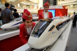 Dua peragawati menunjukkan model kereta cepat buatan China dalam pameran di Jakarta, 13 Agustus 2015. (Foto: AFP)