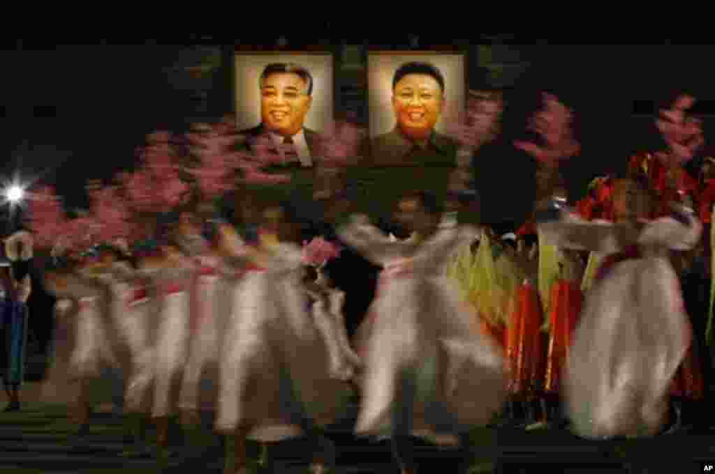 North Korean dancers perform in front of portraits of the late leaders, Kim Il Sung, left, and his son Kim Jong Il, at Kim Il Sung Square in Pyongyang, North Korea, to celebrate 100 years since the birth of the North Korean founder Kim Il Sung, Monday, Ap