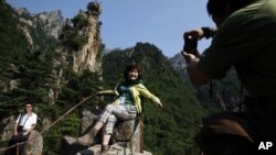 A Chinese tourist poses for a picture near a resort in North Korea's Kumgang Mountains. (2011)