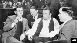 FILE - John Dillinger (C), a well-known gangster, is handcuffed and guarded in court awaiting his trial on Feb. 9, 1934. (AP PHOTO)