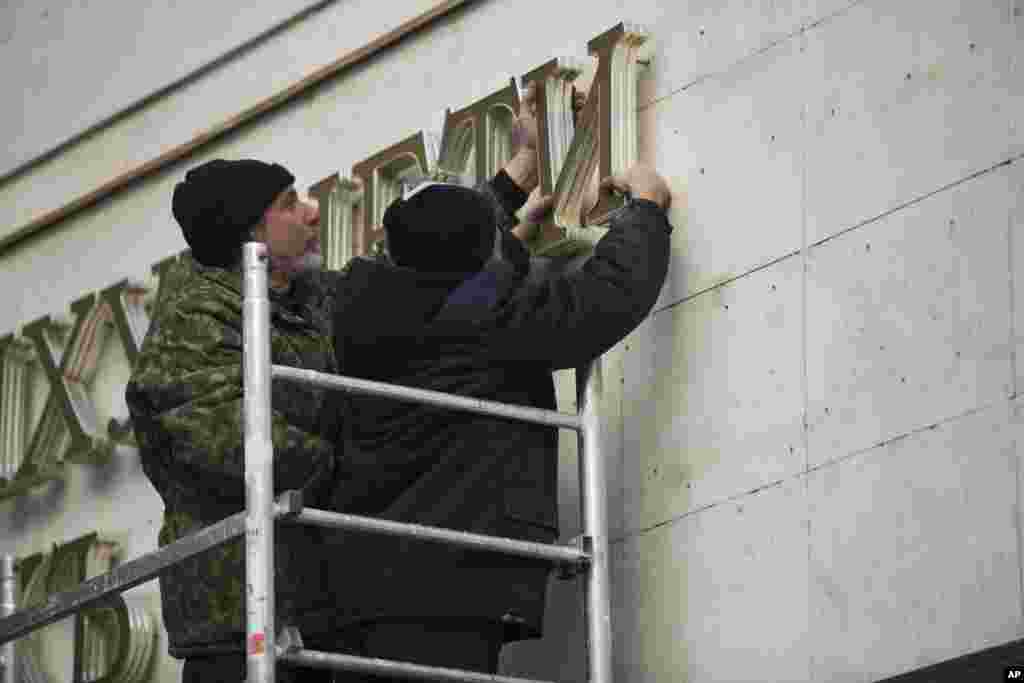 Para pekerja melepas huruf-huruf dari gedung parlemen Krimea di Simferopol (18/3). (AP/Alexander Khitrov)