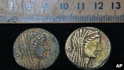 An undated handout picture released by Egypt's Supreme Council of Antiquities shows two coins dating back to the era of Ptolemy III 222-246 BC, discovered in an Egyptian oasis, south of the capital Cairo, 22 Apr 2010