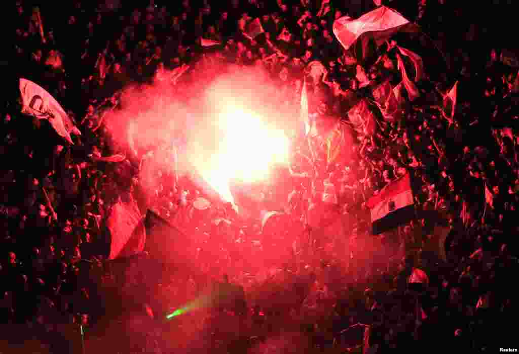 Protesters opposing President Mohamed Morsi gather around a lit flare in Tahrir Square in Cairo, July 3, 2013. 