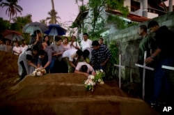 Relatives place flowers after the burial of three victims of the same family, who died at Easter Sunday bomb blast at St. Sebastian Church in Negombo, Sri Lanka, April 22, 2019.