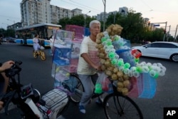 Un vendedor ambulante oferta aves en bicicleta en la carretera de Beijing, el martes 15 de agosto de 2023. El líder chino Xi Jinping pidió paciencia en un discurso en que dijo que su gobierno intenta revertir una crisis económica cada vez más profunda.