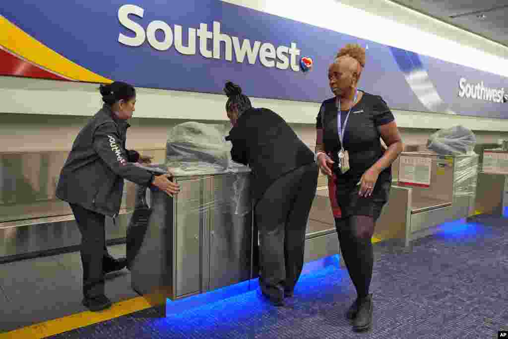 Southwest Airlines employees cover the ticket counters with plastic wrap just before Tampa International Airport was closing due to the possible arrival of Hurricane Milton, Oct. 8, 2024, in Tampa, Florida.