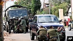 Army soldiers take cover behind their vehicles during a shootout between rival Madagascan security forces in the streets of the capital Antananarivo, 20 May 2010