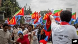 FILE - Eritrean refugees and dissidents, some holding Eritrean flags and some dressed as Eritrean military members to illustrate beatings and torture, left, demonstrate against repressions in their home country in Addis Ababa, Ethiopia, June 23, 2016.