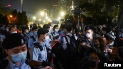 La gente mira a los oficiales de policía que hacen guardia en el Parque Victoria en el 32 aniversario de la represión de los manifestantes a favor de la democracia en la Plaza de Tiananmen de Beijing en 1989, en Hong Kong, el 4 de junio de 2021.